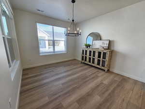 Dining room with hardwood / wood-style floors, a notable chandelier, and a textured ceiling