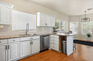 Kitchen featuring dishwasher, light hardwood / wood-style floors, sink, and white cabinetry