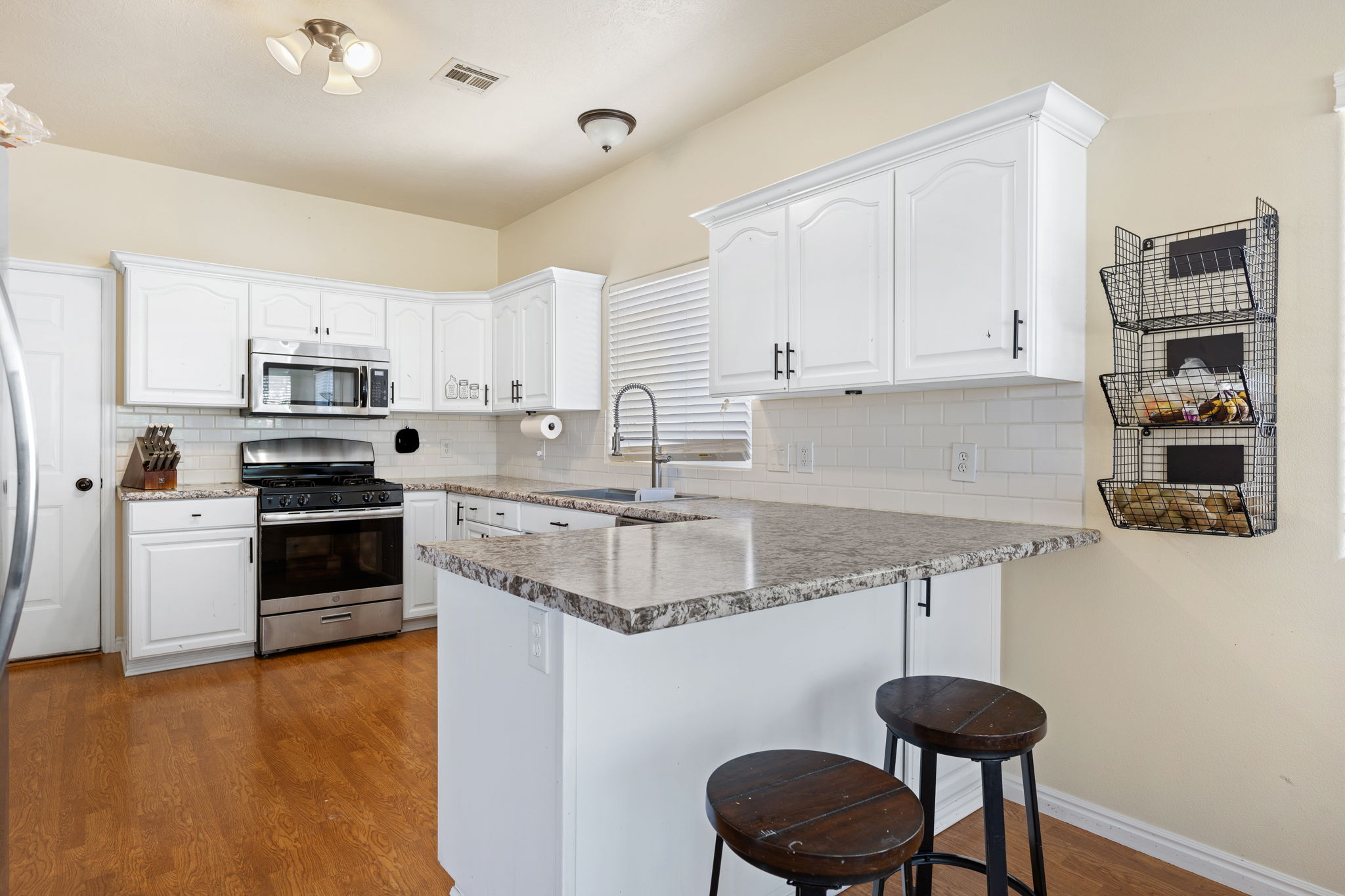 Kitchen with appliances with stainless steel finishes, sink, dark wood-type flooring, and white cabinets