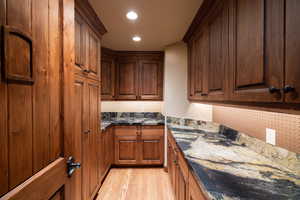 Kitchen with dark stone counters and light hardwood / wood-style floors