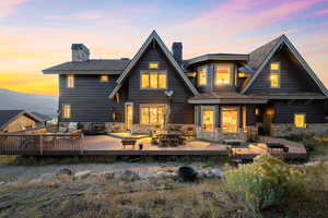 Back house at dusk featuring a wooden deck and an outdoor hangout area