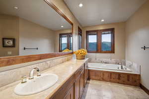 Bathroom with vanity, a bathing tub, tile patterned flooring, and a wealth of natural light