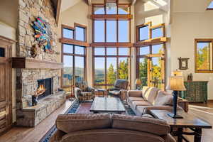 Living room with light wood-type flooring, a wealth of natural light, a fireplace, and high vaulted ceiling