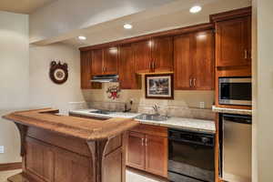 Kitchen featuring black dishwasher, a breakfast bar area, stainless steel microwave, and sink