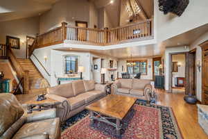 Living room featuring a notable chandelier, a fireplace, a towering ceiling, and light hardwood / wood-style floors