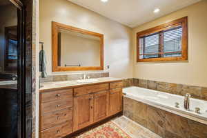 Bathroom featuring a relaxing tiled tub and vanity