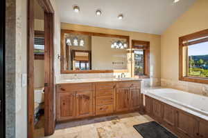 Bathroom featuring lofted ceiling, a bath, vanity, and toilet