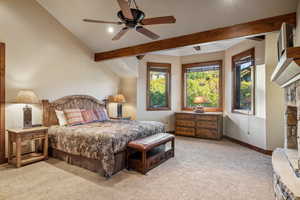 Carpeted bedroom featuring ceiling fan and beamed ceiling