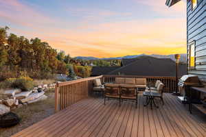 Deck at dusk with a mountain view, an outdoor living space, and area for grilling