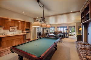 Recreation room featuring a stone fireplace, light colored carpet, and pool table