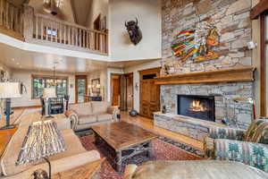 Living room featuring a notable chandelier, a high ceiling, hardwood / wood-style flooring, and a fireplace