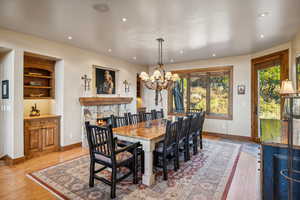 Dining space featuring an inviting chandelier, light wood-type flooring, and a fireplace