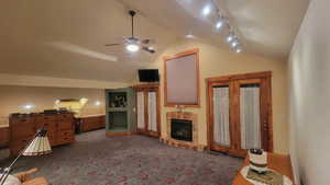 Carpeted living room with vaulted ceiling, ceiling fan, and track lighting