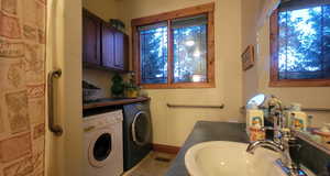 Laundry area featuring washer and clothes dryer, light tile patterned floors, and sink