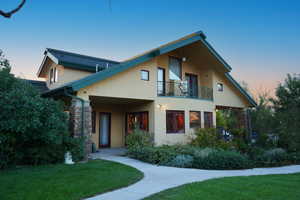 View of front of house with a balcony and a lawn