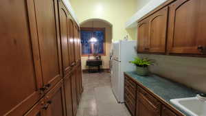 Kitchen featuring hanging light fixtures, sink, and white refrigerator