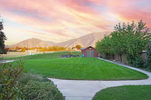 Yard at dusk featuring a mountain view and a shed