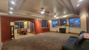 Home theater room featuring a tray ceiling, ceiling fan, and light colored carpet