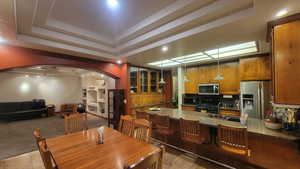 Kitchen with a raised ceiling, hanging light fixtures, sink, appliances with stainless steel finishes, and dark stone counters