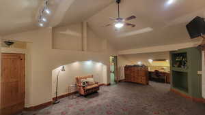 Sitting room with carpet floors, track lighting, ceiling fan, and high vaulted ceiling