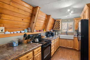 Kitchen featuring sink, dark wood-type flooring, a textured ceiling, and black appliances