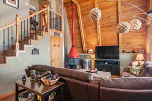 Living room featuring beam ceiling, wood-type flooring, wooden ceiling, a fireplace, and a towering ceiling