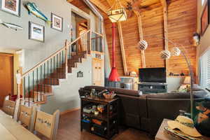 Living room with beam ceiling, hardwood / wood-style floors, high vaulted ceiling, and wooden ceiling