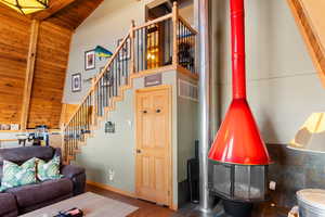 Living room with wood ceiling, beam ceiling, dark wood-type flooring, and a wood stove