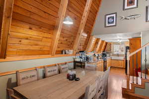 Dining area with light hardwood / wood-style flooring, lofted ceiling with beams, and wooden ceiling