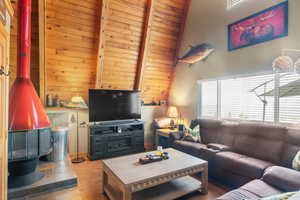 Living room with wood-type flooring, vaulted ceiling with beams, wooden ceiling, and wooden walls