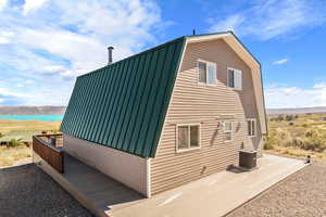 View of home's exterior with a deck with water view and central air condition unit