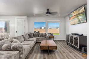 Living room with a textured ceiling, wood-type flooring, and ceiling fan