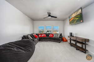 Carpeted living room with ceiling fan and a textured ceiling