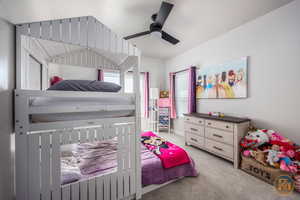 Bedroom with light carpet, ceiling fan, and a textured ceiling