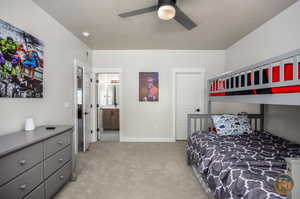 Carpeted bedroom with a textured ceiling, ensuite bath, and ceiling fan