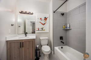 Full bathroom with tile patterned floors, tiled shower / bath, vanity, and toilet