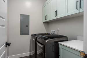 Laundry area featuring washing machine and dryer, electric panel, dark wood-type flooring, and cabinets