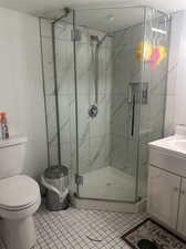 Bathroom featuring walk in shower, vanity, toilet, and tile patterned floors