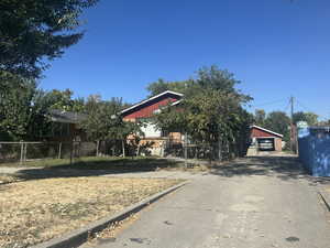 View of property hidden behind natural elements featuring a garage and an outbuilding