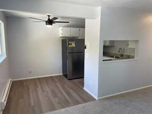 Kitchen featuring a baseboard heating unit, wood-type flooring, sink, stainless steel refrigerator, and ceiling fan