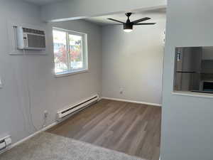 Unfurnished room with baseboard heating, ceiling fan, and hardwood / wood-style flooring