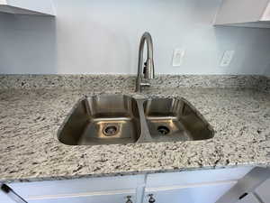 Details featuring light stone countertops, sink, and white cabinets