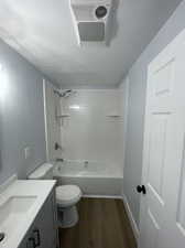 Full bathroom featuring wood-type flooring, a textured ceiling, tiled shower / bath combo, vanity, and toilet