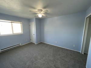 Spare room featuring carpet, ceiling fan, and a baseboard radiator