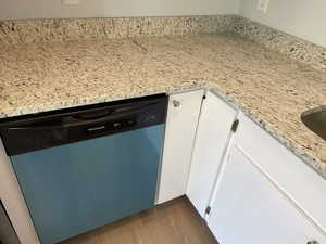 Room details featuring light stone countertops, dishwasher, dark hardwood / wood-style floors, and white cabinetry