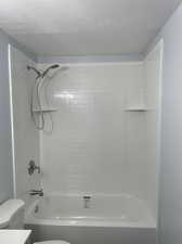 Full bathroom with a textured ceiling, vanity, toilet, and tiled shower / bath