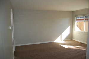 Carpeted empty room featuring brick wall