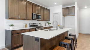 Kitchen featuring light hardwood / wood-style floors, a kitchen island with sink, appliances with stainless steel finishes, and sink