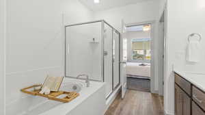 Bathroom featuring ceiling fan, hardwood / wood-style flooring, vanity, and separate shower and tub