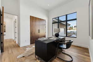 Home office with a high ceiling and light wood-type flooring